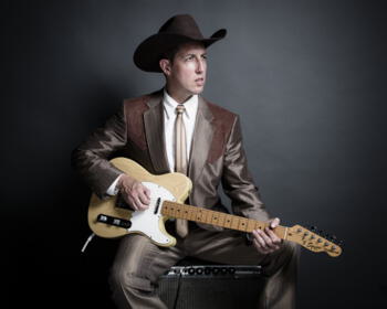 Foto: Alistair Christl in Cowboy-Outfit mit Gitarre